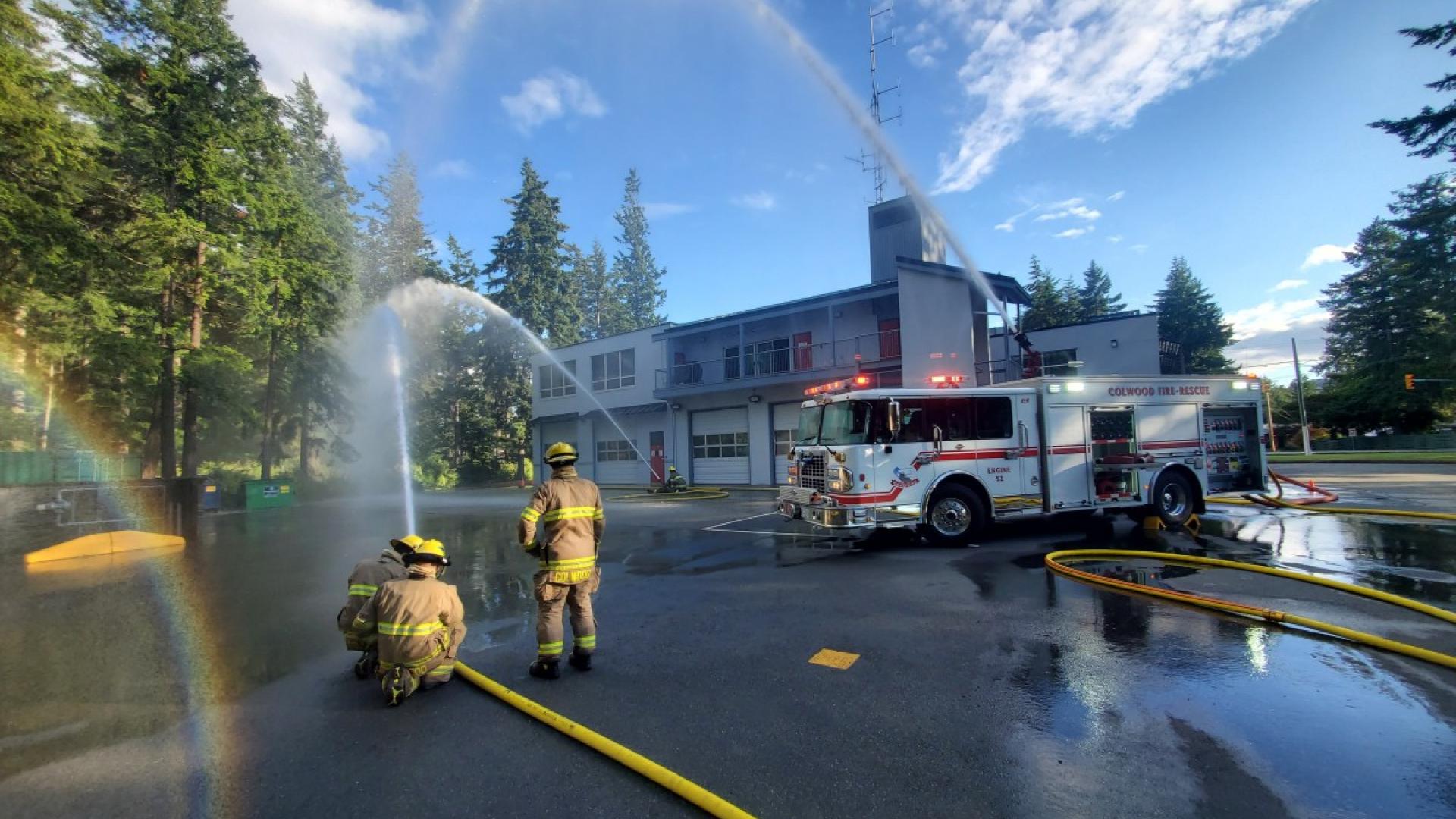 firefighters spray hoses at fire hall