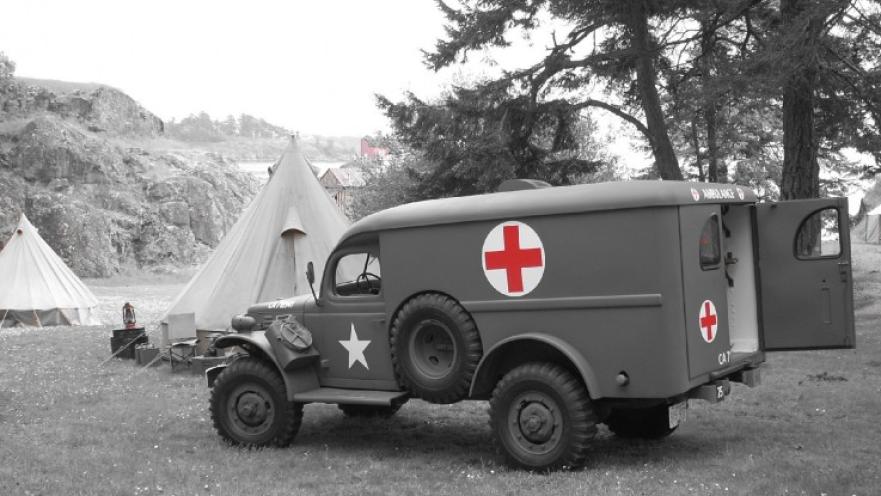 Vintage ambulance parked near some tentns.