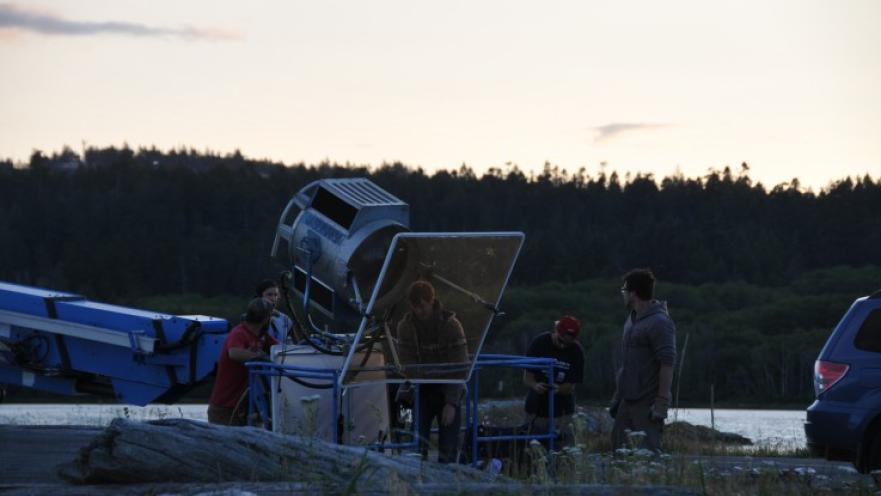 Film crew setting up lighting equipment as the sun is setting.