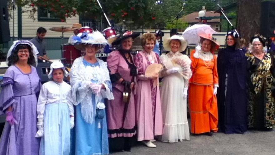 Row of women dressed in old-timey dresses.