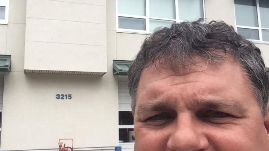 Selfie of man with grey moustache standing in front of Colwood's fire department building.