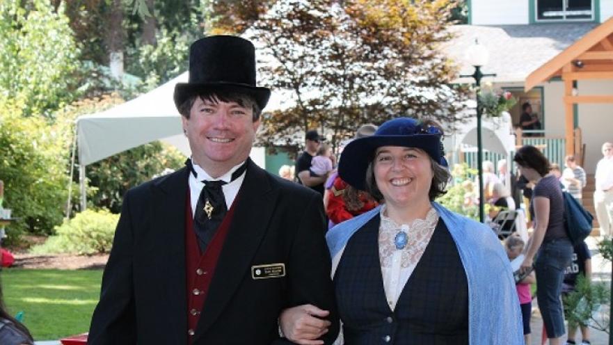 Man and woman dressed in old-timey clothing. The subjects are smiling.