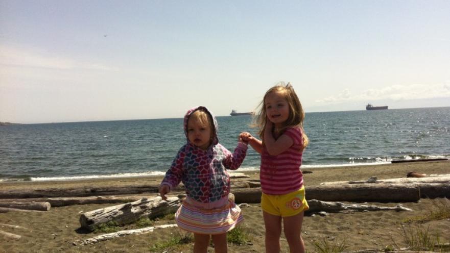 Two girls standing on a beach.