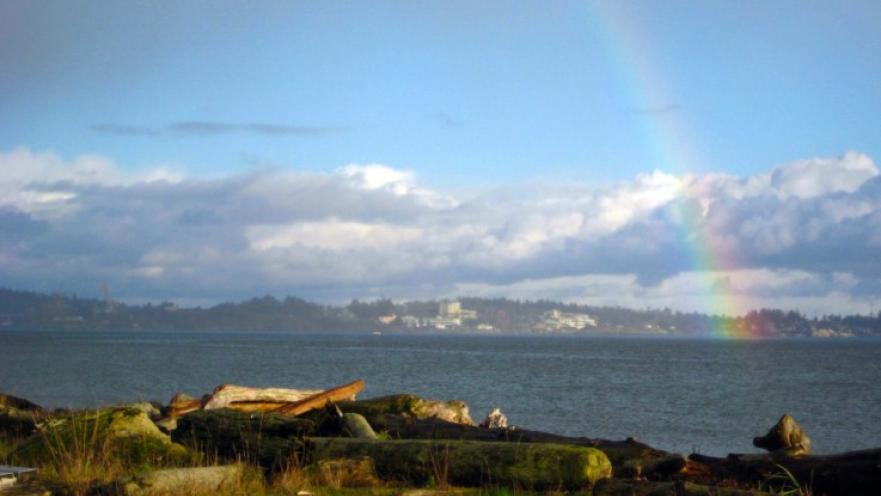 Rainbow arching over lagoon. The sky is cloudy in the background.