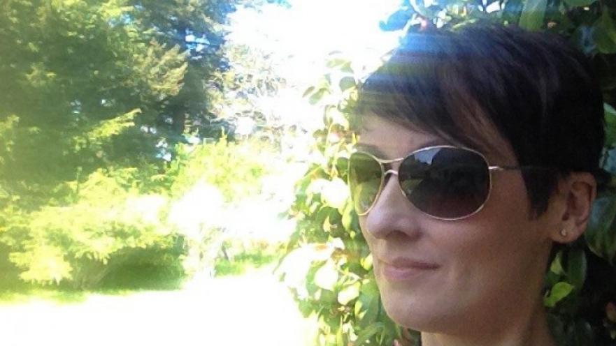 Selfie of woman wearing dark sunglasses. The subject has short brown hair.