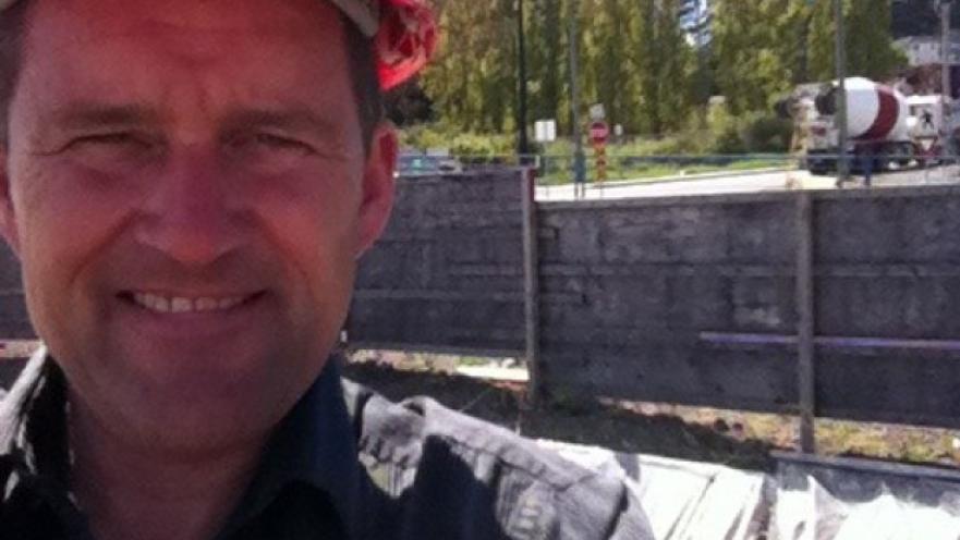 Selfie of a construction worker. The subject is wearing a red construction helmet.