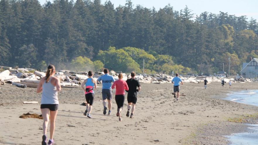 Group of people running on the beach.