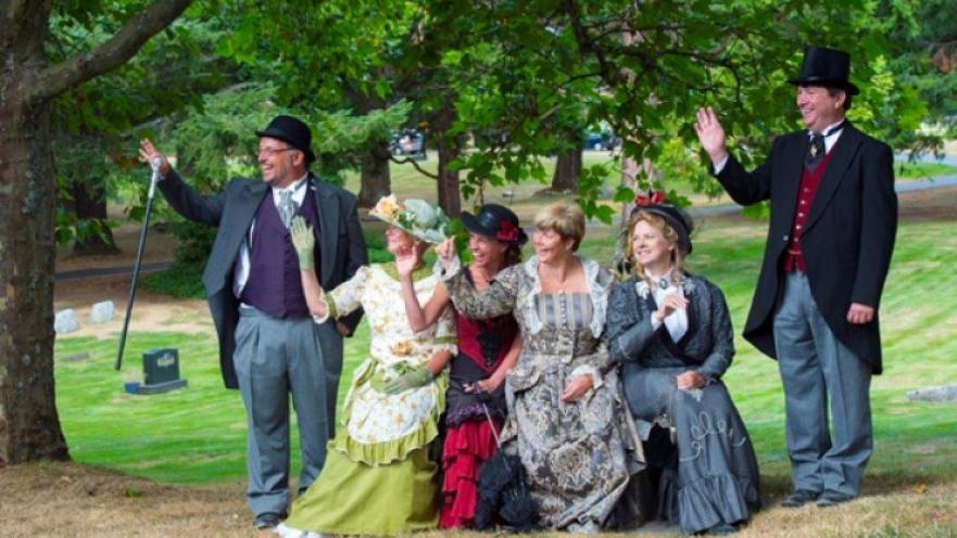 Group of people with wearing old-timey clothes smiling for photo.