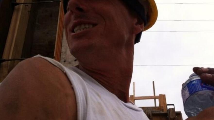 Construction worker smiling. The subject is wearing a yellow construction helmet.