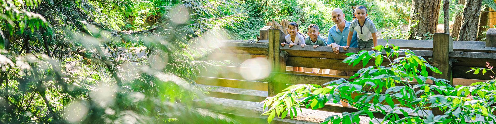 young family on bridge in park with green leaves