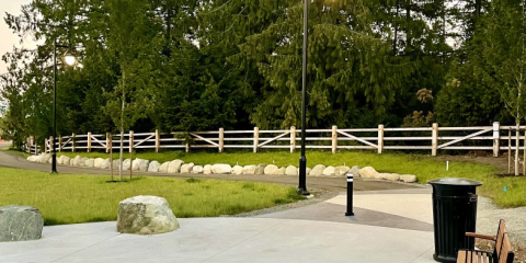 Fenced park area in Colwood with a pathway and streetlights.