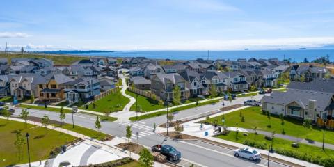 Aerial view of a residential neighbourhood with modern houses and green lawns near the coastline.