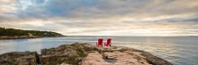 parks canada red adirondak chairs on the rocks overlooking the ocean