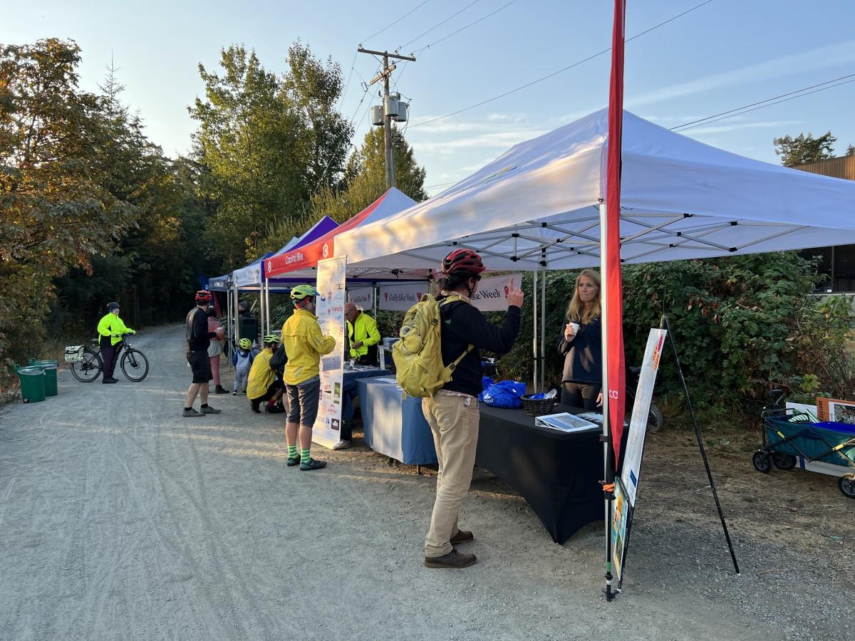 Outdoor event setup with tents and people talking during a biking event.