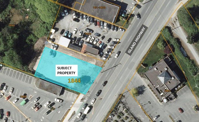 Aerial view of a property labeled "Subject Property" highlighted in blue, located at 1844 Island Highway. Surrounding areas include parking lots with numerous cars, adjacent buildings, and a main road labeled Island Highway.