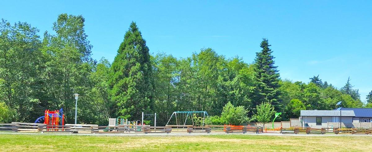 Children's playground with swings and slides next to a building.