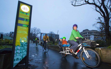 People riding bicycles on a rainy day near a bike counter display.