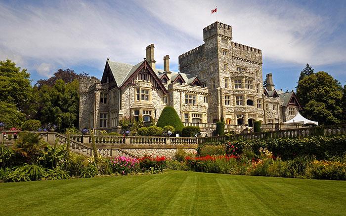 Exterior view of Hatley Castle, a historic stone building with well-manicured gardens.