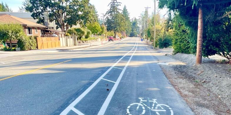 A newly paved road with a dedicated bike lane marked with a bicycle symbol.