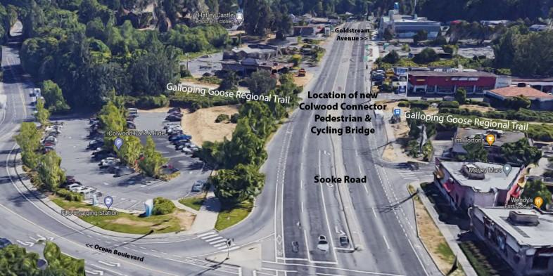 Aerial view of Sooke Road, showing the location for the new Colwood Connector Pedestrian & Cycling Bridge. The area includes the Galloping Goose Regional Trail, a parking lot, various buildings, and marked roads.