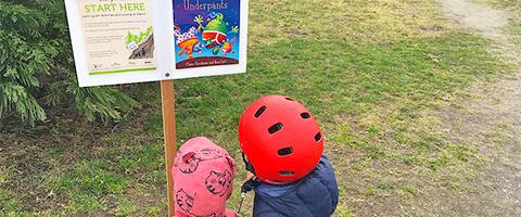 kids looking at story walk page in park